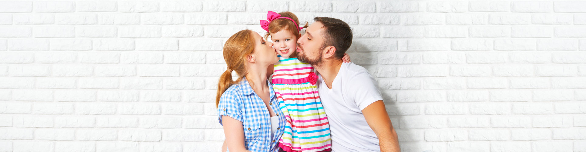 parents kissing their daughter